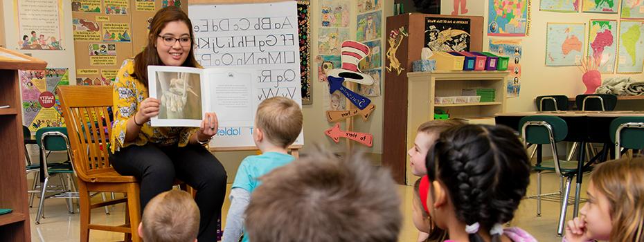 A student teacher reading to elementary students