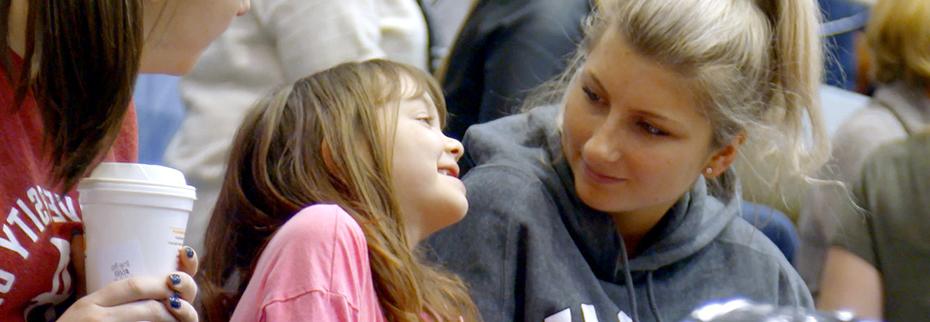 一名学生和她微笑的好友博纳一起看篮球比赛.